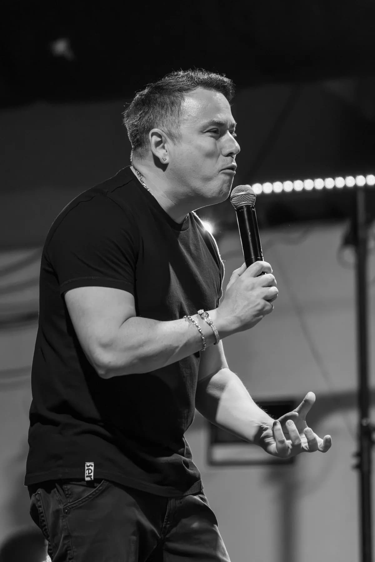 Black-and-white photograph of a performer speaking into a microphone