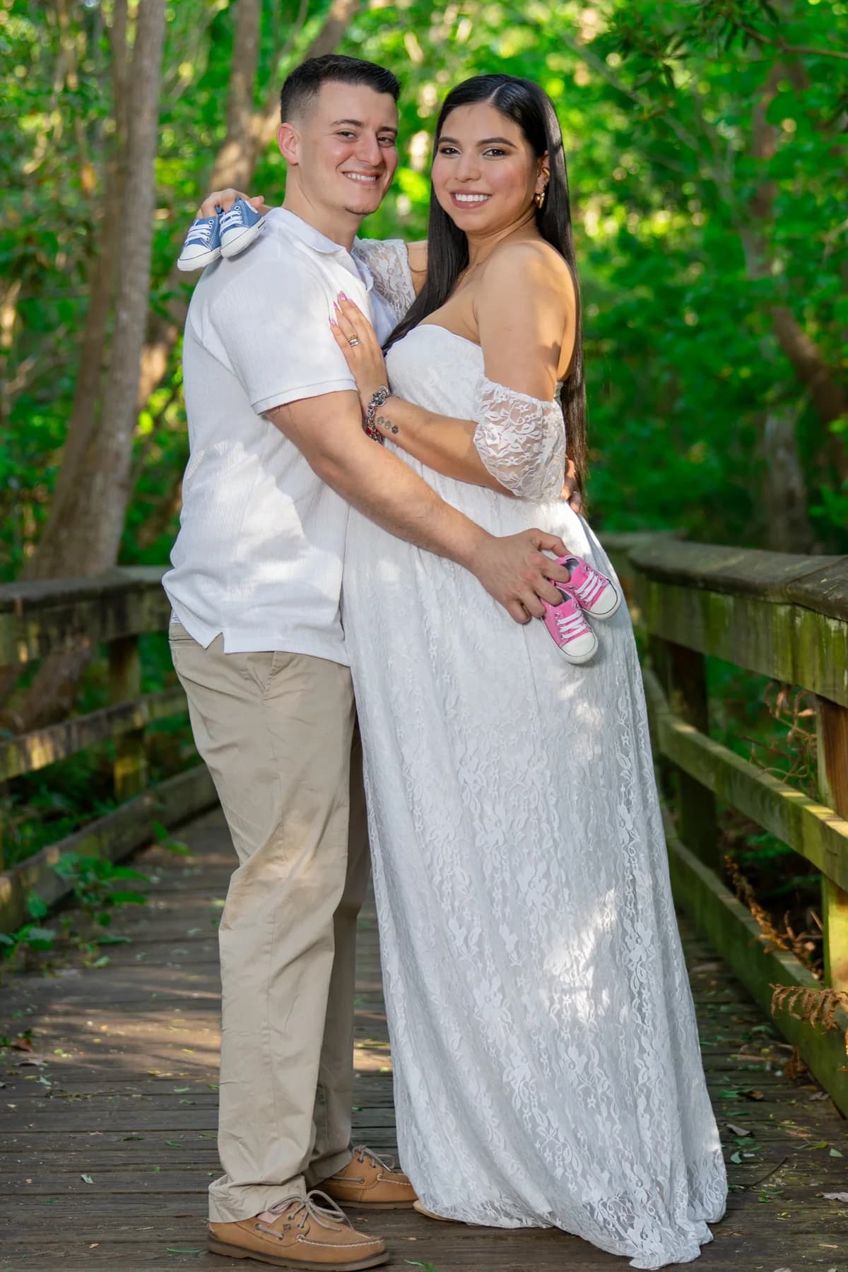 Two people standing together in white clothing on a wooded boardwalk