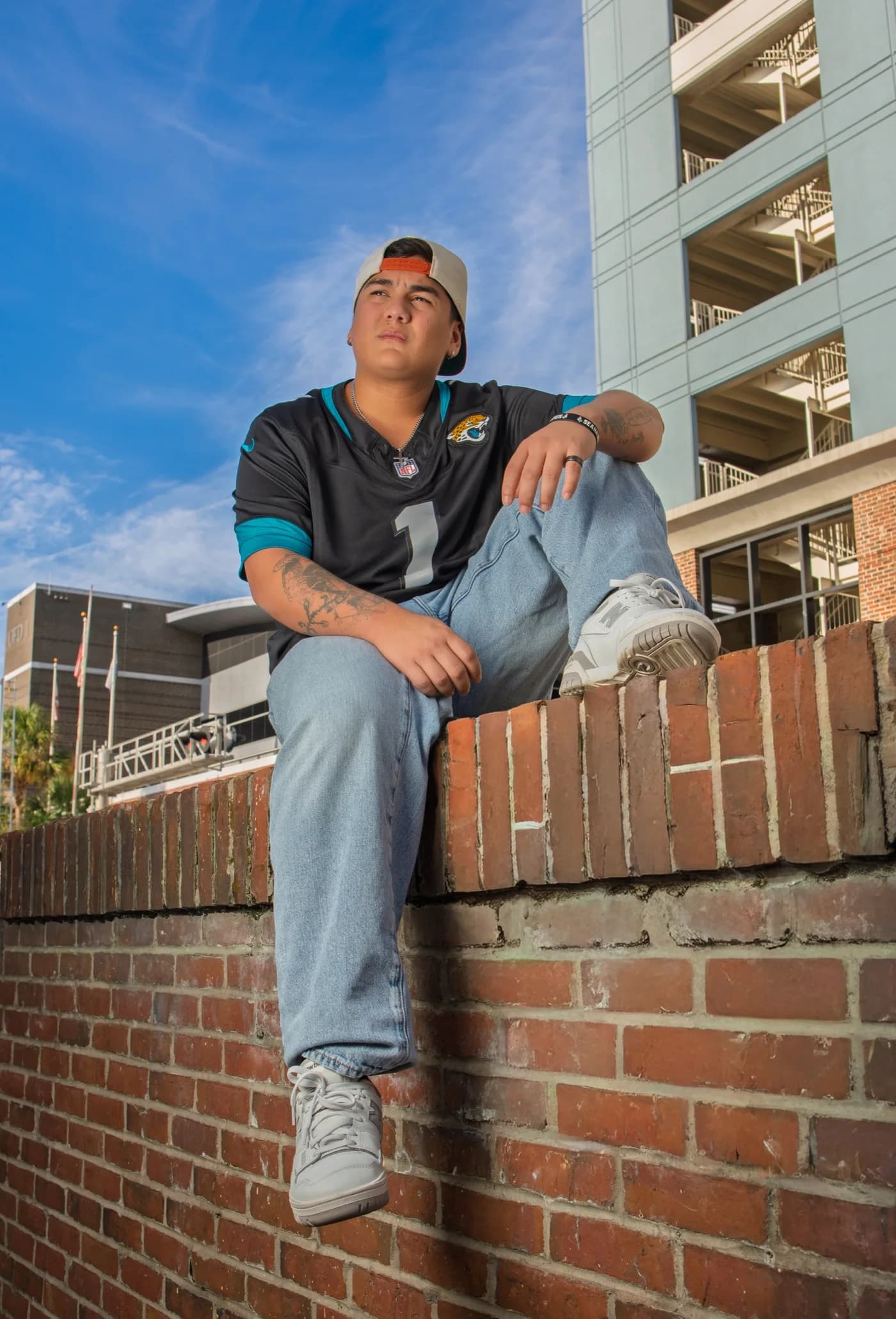 A person seated on a brick ledge outdoors beneath a blue sky
