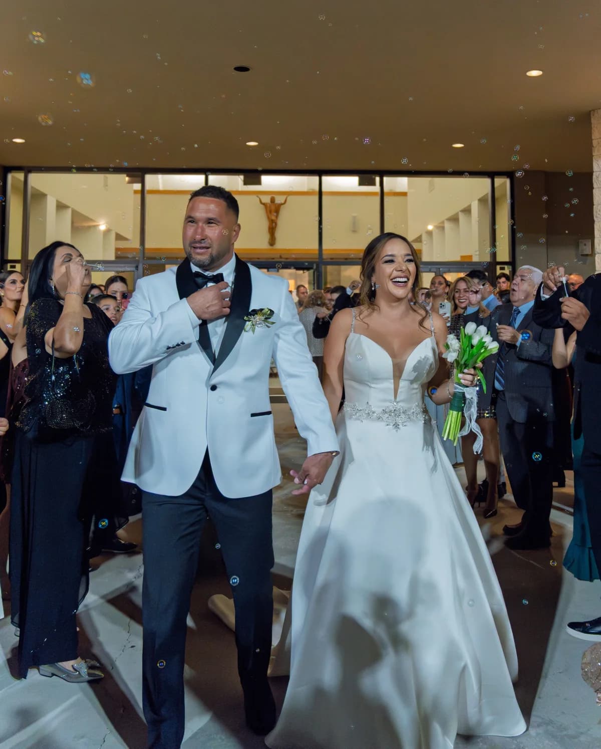 A wedding couple entering a celebration amid guests and falling confetti